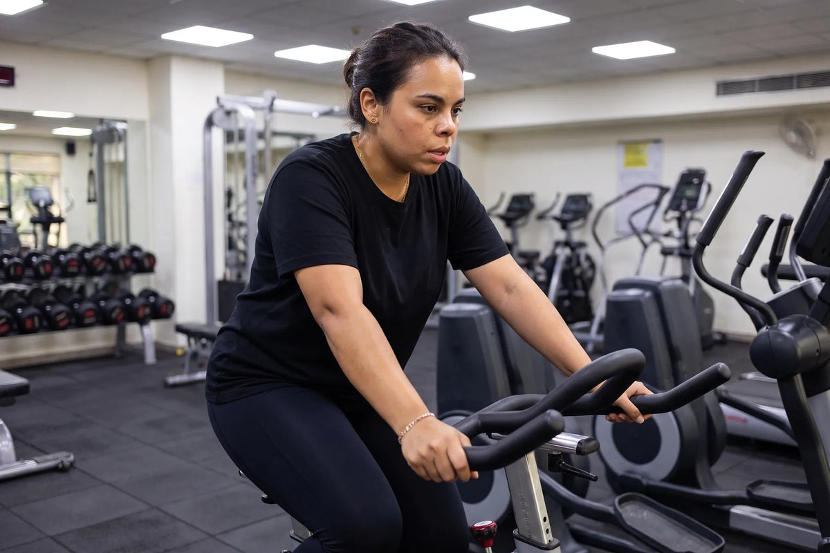 Cycling on a stationary bike at a gym, mid-effort
