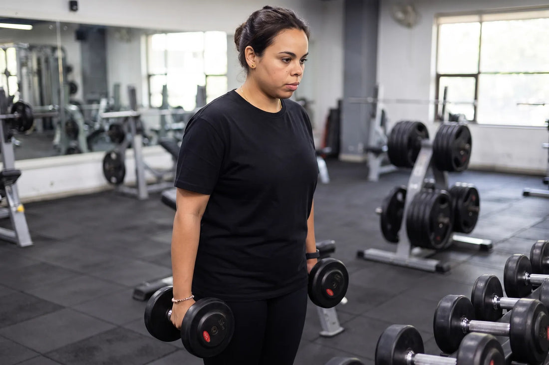 Lifting dumbbells at a gym rack, mid-set