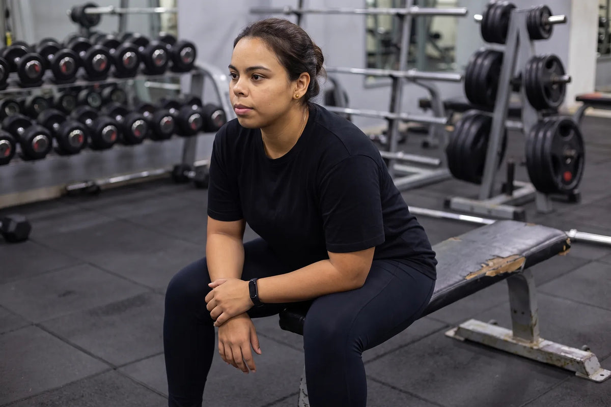 Sitting between sets on a weights bench at a gym