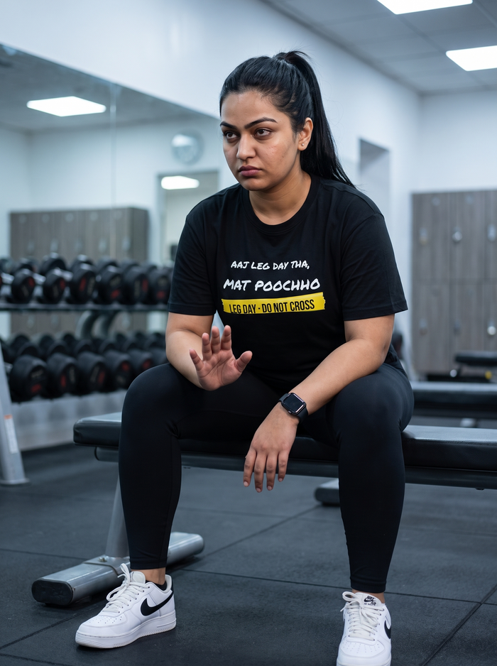 Mat Poochho box fit gym t shirt for women in Black, worn by a model sitting on a gym bench between sets