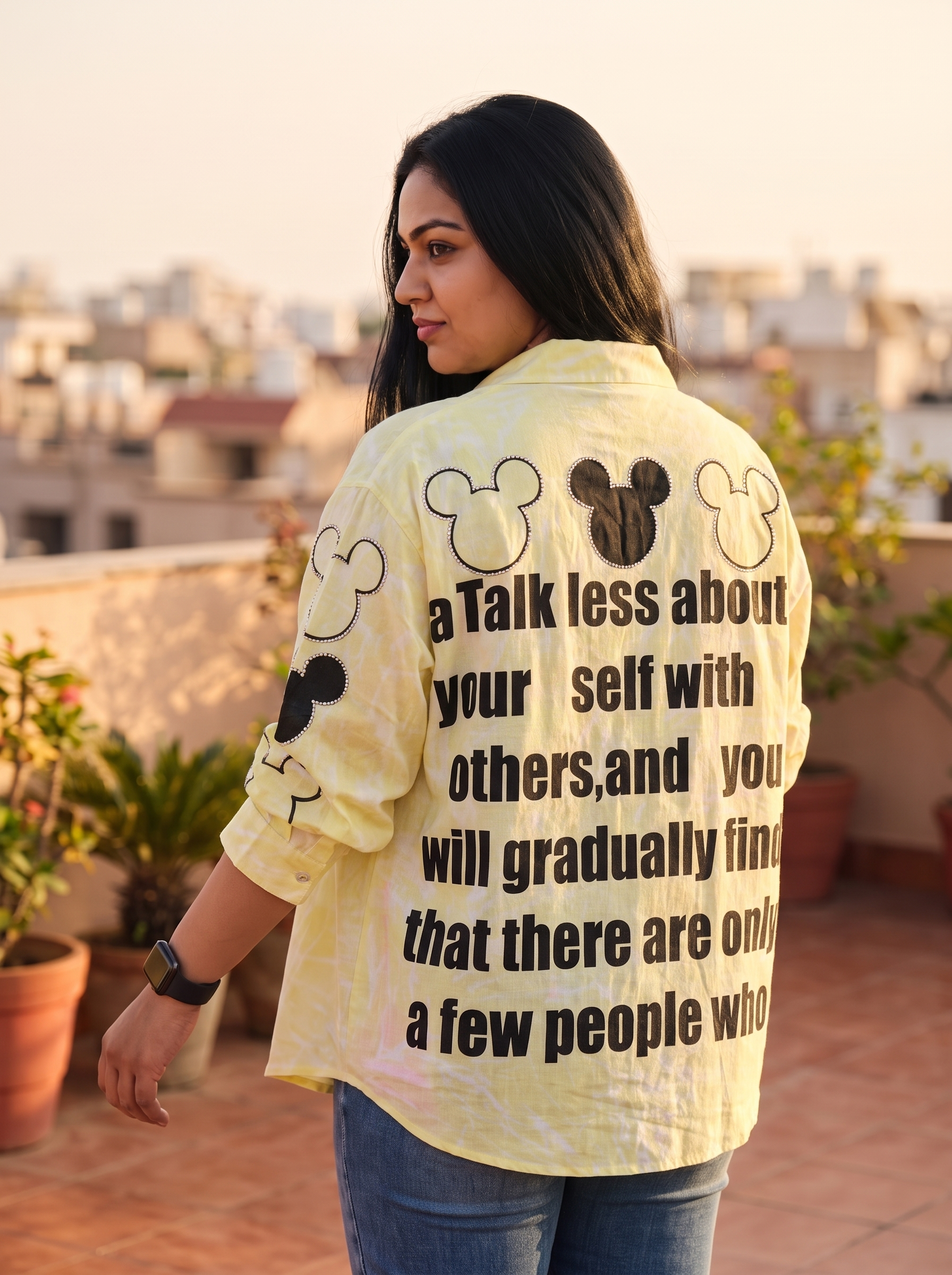 Talk Less oversized Kora cotton shirt in lemon yellow, back view with rhinestone traced print, worn open over a camisole and denim
