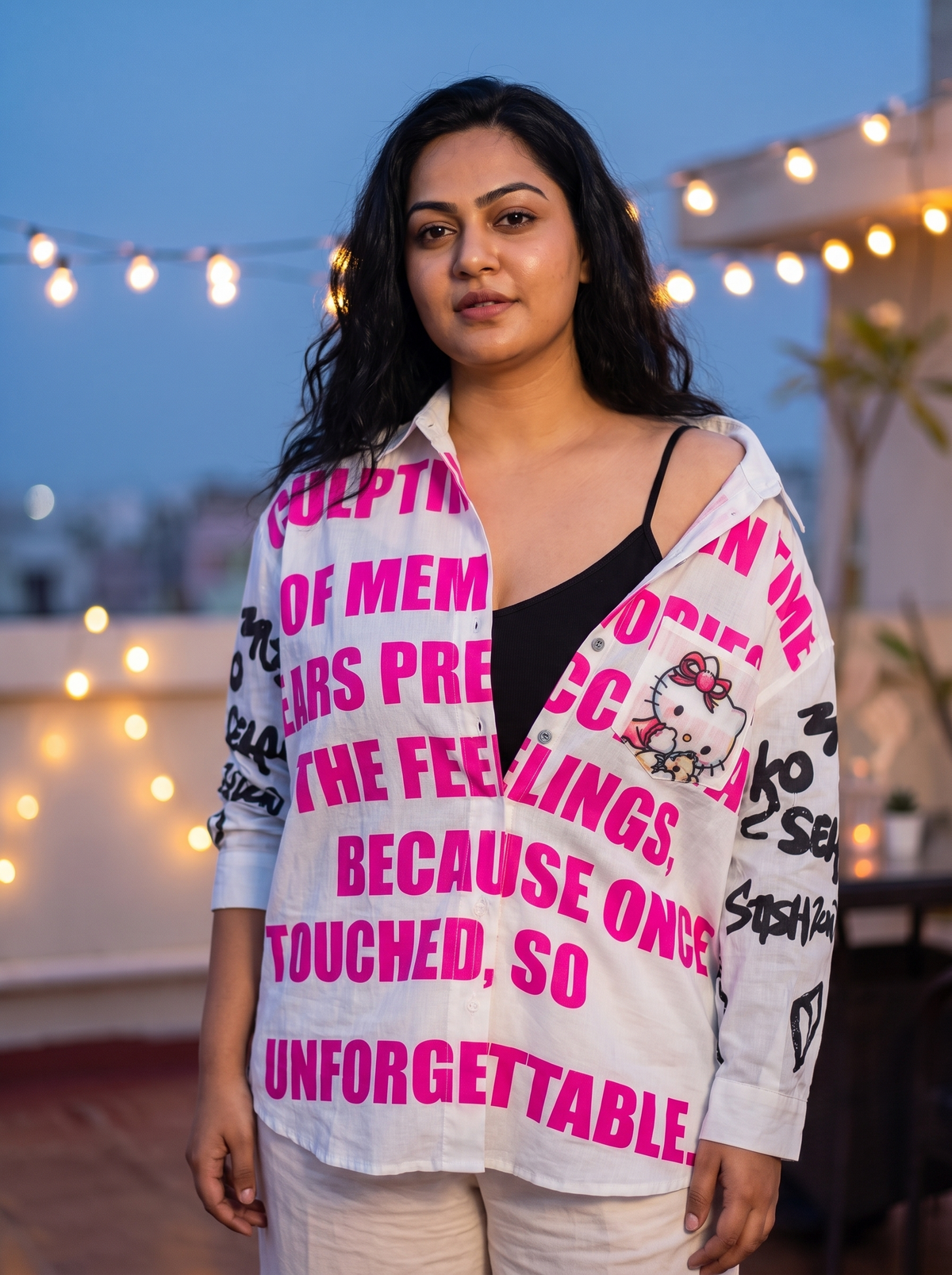 Unforgettable oversized Kora cotton shirt in white worn open at a rooftop party at dusk